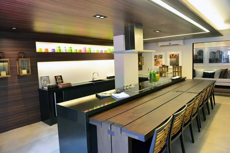 Área gourmet com bancada em pedra e mesa de madeira